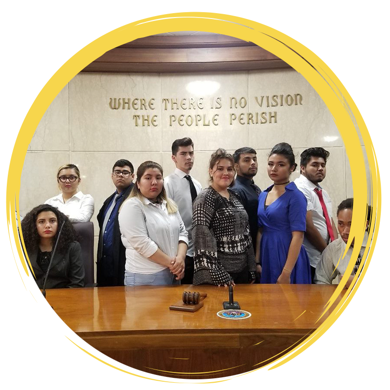 High school students smiling together in at desk in courtroom for mock trial